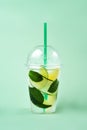 Lemonade to go cup with mint, lime, lemon and cucumber on green background