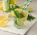 Lemonade in a transparent glass with lemon, lime, rosemary sprigs and mint leaves on a white background Royalty Free Stock Photo