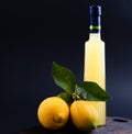 Lemoncello in a bottle on a black background, Traditional Italian liqueur from lemons. Alcohol yellow and fresh lemon with green