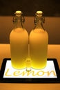 Lemoncello cocktail in two big bottles on table lighted by tablet underneath in cafe