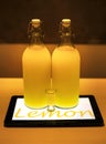 Lemoncello cocktail in two big bottles on table lighted by tablet underneath in cafe