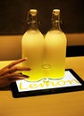 Lemoncello cocktail in two big bottles on table lighted by tablet underneath in cafe