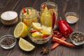 Lemons and chili pepper in jars, spices and salt on table