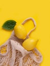 Lemons in an eco-bag on a yellow background.