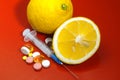Lemons on a red background with syringes and pills. Medical preparations and vitamin C
