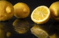 Lemons on a wet black with reflection , half, slices and whole citrus, close up, copy space