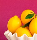 Lemons in a white bowl with magenta background