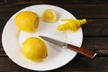 Lemons on white plate, knife and sprayer fresh juice, on wooden surface Royalty Free Stock Photo