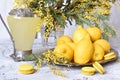 Lemons, yellow spring mimosa flowers and a decanter of lemon drink.