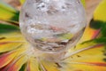 Lemurian Clear Quartz Sphere crystal magical orb in the middle of a circle made of colorful feathers.