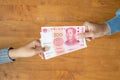 Lend or Giving money concept. Top view hand giving banknote currency Chinese Yuan (CNY or RMB