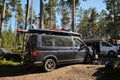 Leningrad Region, Russia - June 2022. Stylish black Volkswagen transporter with sup surfs on roof. Camping for campers