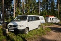 Leningrad Region, Russia - June 2022. Volkswagen transporter T4 minivan is white in front, and Dodge with trailer in