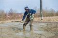 A guest worker with a deep vibrator levels concrete mortar on the foundation