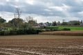 Lennik, Flemish Brabant, Belgium, - Brown soil of harvested agriculture fields with a cultural center in the background