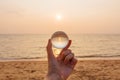 Lens ball in hand with reflection of sea and sunset on the beach Royalty Free Stock Photo