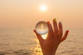 Lens ball in hand with reflection of sea and sunset on the beach Royalty Free Stock Photo