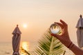 Lens ball in hand with reflection of sea and sunset on the beach Royalty Free Stock Photo