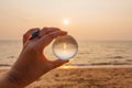 Lens ball in hand with reflection of sea and sunset on the beach Royalty Free Stock Photo