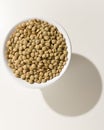 Lentil legume. Grains in a bowl. Shadow over white table.
