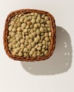 Lentil legume. Wicker basket with grains. Top view, hard light.