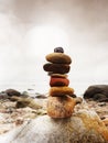 Balanced stone pyramid on sea shore, waves in background. Colorful stones Royalty Free Stock Photo