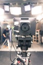 Film camera in broadcasting studio, spotlights and equipment, cameraman in the blurry background