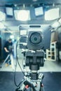 Film camera in broadcasting studio, spotlights and equipment, cameraman in the blurry background