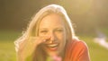 LENS FLARE: Beautiful young woman lying in a meadow and laughing to a joke. Royalty Free Stock Photo