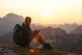 LENS FLARE: Unrecognizable girl observes the sunset above the Alps with her dog. Royalty Free Stock Photo