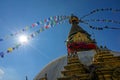 LENS FLARE: Colorful prayer flags flutter in wind blowing over top of a stupa Royalty Free Stock Photo