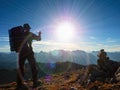 Lens flare defect. Tourist guide on Alps peak takes photo. Strong hiker with big backpack