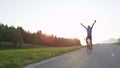 LENS FLARE: Ecstatic cyclist looking into the evening sky and outstretching arms