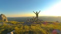 LENS FLARE: Excited athletic man celebrates reaching top of the hill on bike.