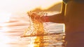 LENS FLARE: Golden evening sunbeams shine on young woman splashing ocean water. Royalty Free Stock Photo