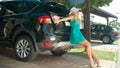 LENS FLARE: Happy woman leaning on the lid of her car to close the stuffed trunk