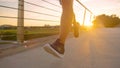 LOW ANGLE: Athletic young man runs across an asphalt bridge on a sunny evening.