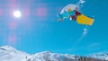 LENS FLARE: Male snowboarder jumps and does a stunning rotating grab stunt. Royalty Free Stock Photo