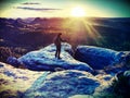 Lens flare. Tourist guide on peak takes photo. Strong hiker with backpack