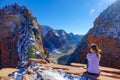 LENS FLARE: Traveler girl sits and observes the canyon from Angel\'s Landing.