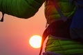 LENS FLARE: Unrecognizable trekker in green jacket observes the stunning sunset. Royalty Free Stock Photo