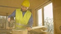 LENS FLARE: Worker building a hardwood house is trimming a gypsum wallboard.