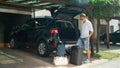 LENS FLARE: Young male traveler packing his luggage in the back of his car.