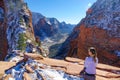 LENS FLARE: Young woman sits and observes the beautiful red canyon in Utah.