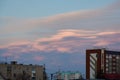 Lenticular clouds in the city above the roofs of high-rise buildings at sunset. Beautiful sky