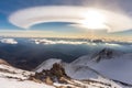 lenticular clouds creating a halo effect on a mountain summit