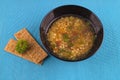 Lentil soup with herbs in black mask on a blue background. Royalty Free Stock Photo