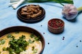 Lentils or pea soup with parsley, onions, garlic, rye bread crackers and aromatic black, red, pink, white pepper set on blue table Royalty Free Stock Photo