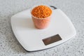 Lentils in a plastic measuring cup on an electronic kitchen scale