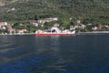 Red ferry sails in bay of Kotor in Adriatic sea near coast